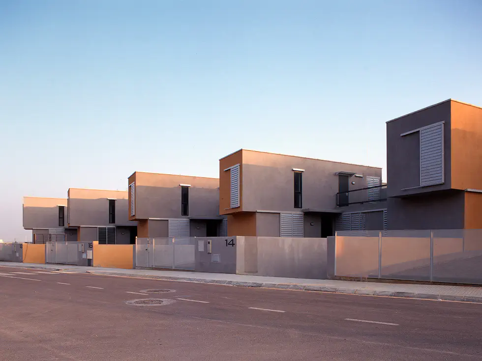 A row of modern, two-story houses with clean lines and minimalist design, featuring large windows and a neutral color palette.
