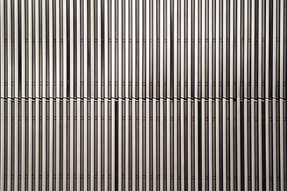 Close-up view of the vertical metal slats forming the facade of Artes High School, creating a dynamic and textured pattern.