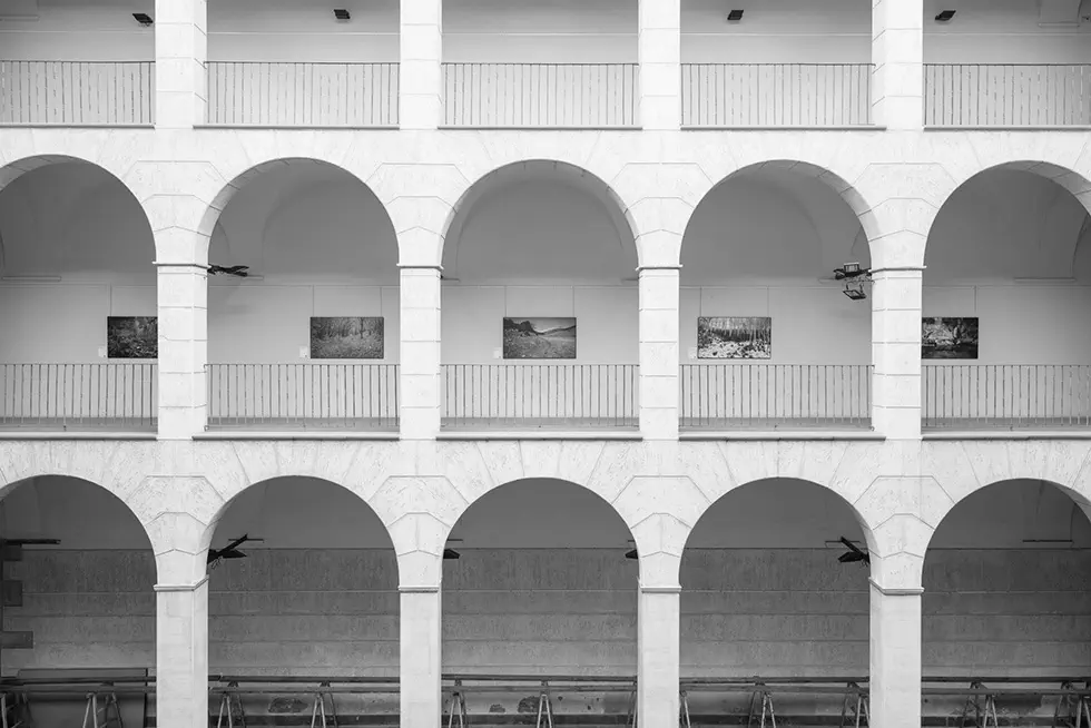 Arched gallery with displayed artworks on the upper level.