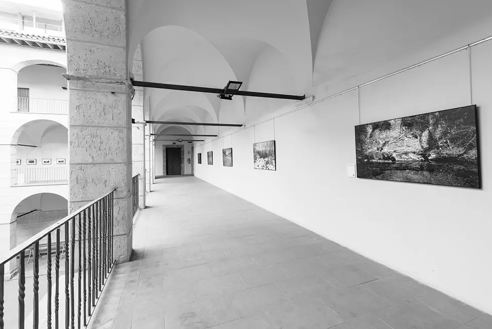 Covered walkway in an art gallery with photographs displayed on the walls.
