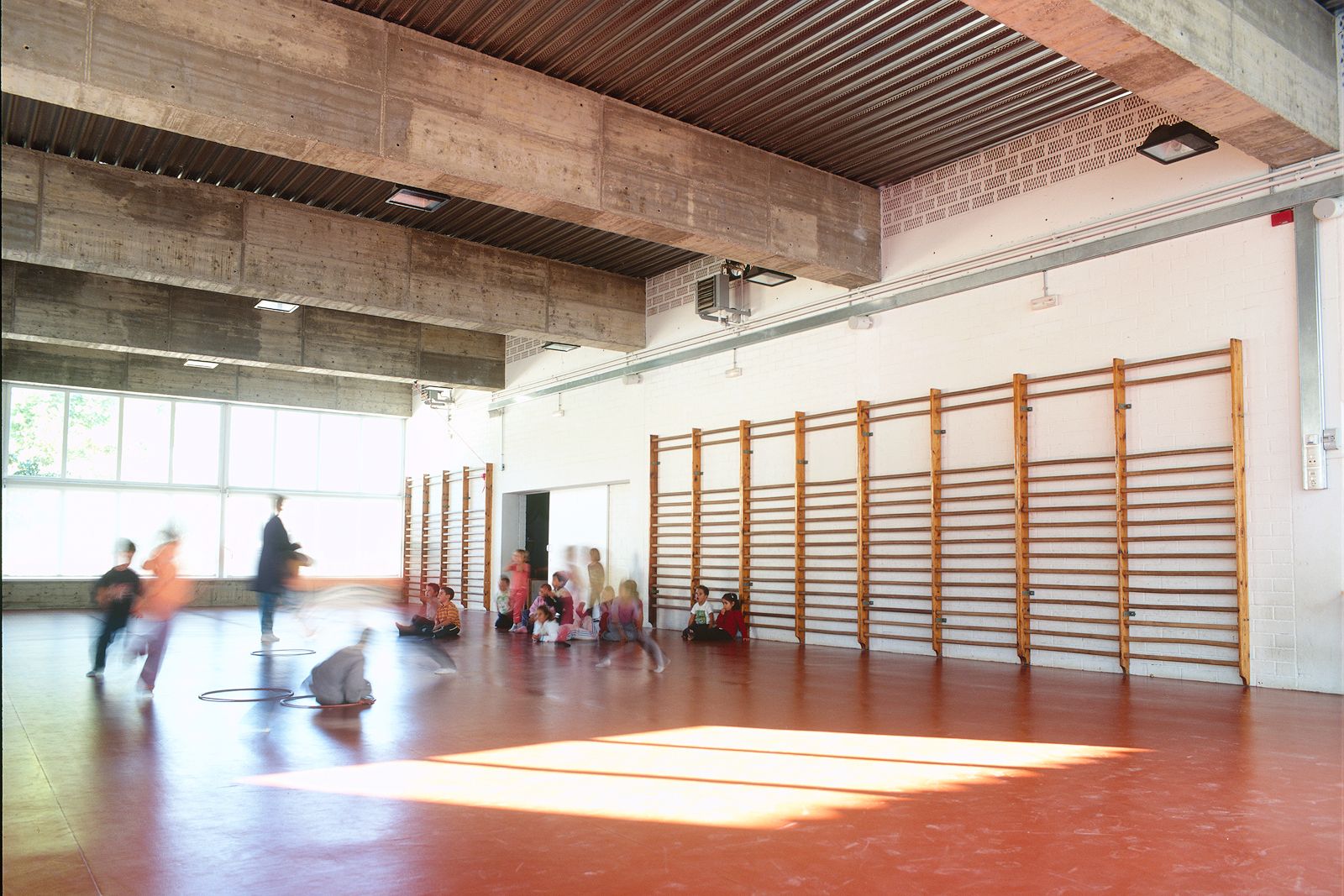 Children playing in a brightly lit school gymnasium.