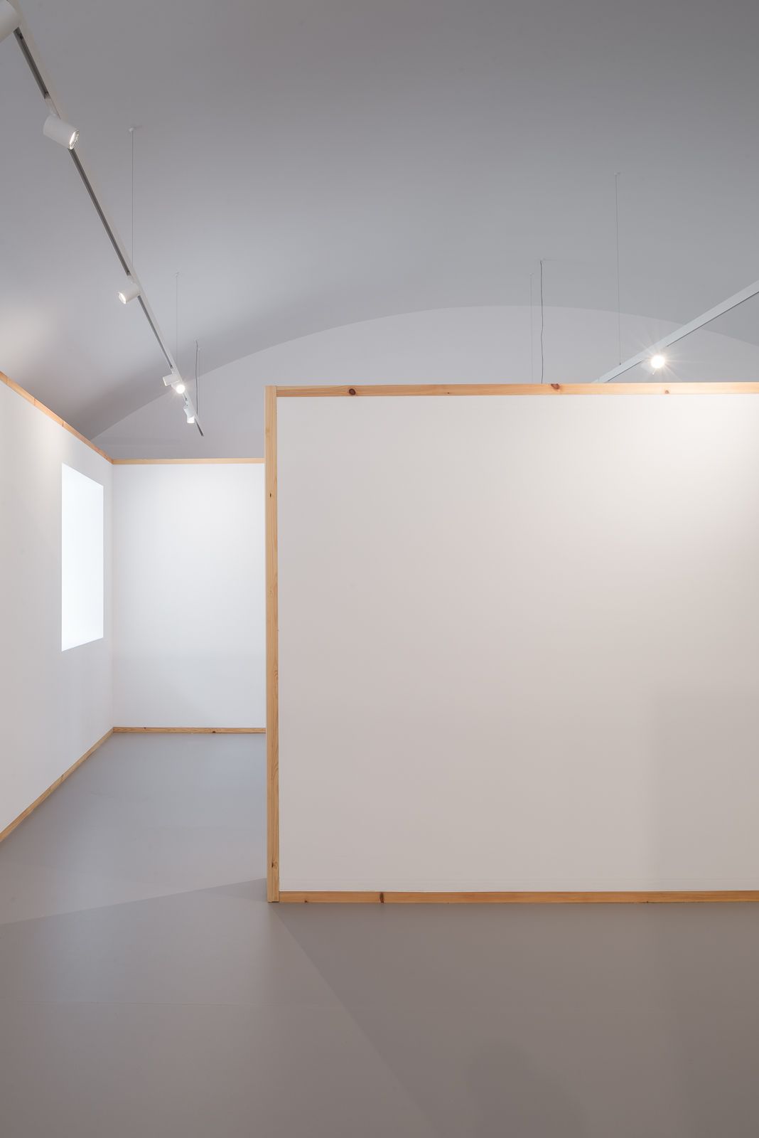 Interior view featuring white partition walls with wooden frames and overhead lighting.