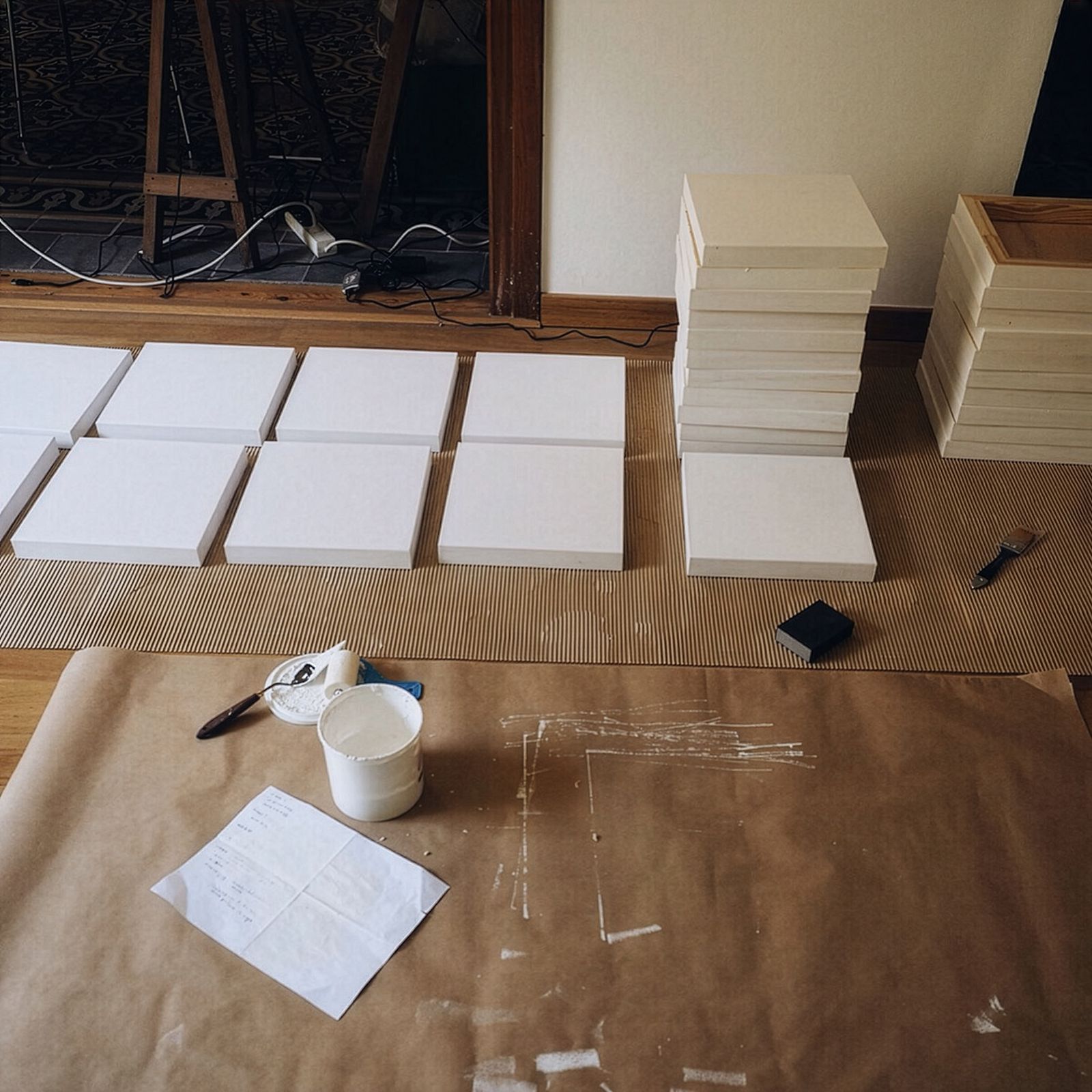 Material artístic, llenços en blanc i piles de marcs disposats al terra, preparats per a la preparació en l'espai de treball d'un artista.