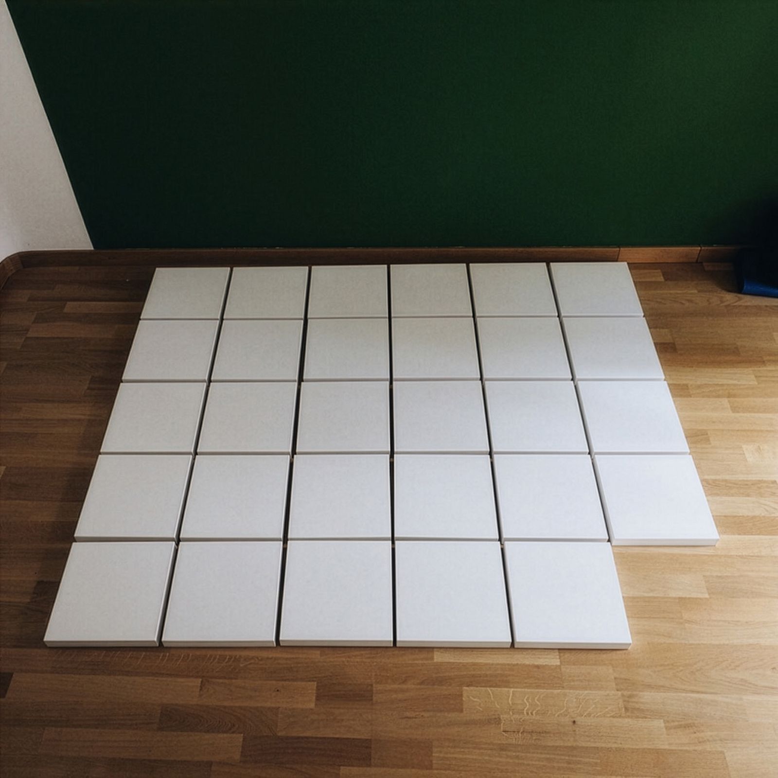 Una graella de llenços quadrats blancs disposats en un terra de fusta.