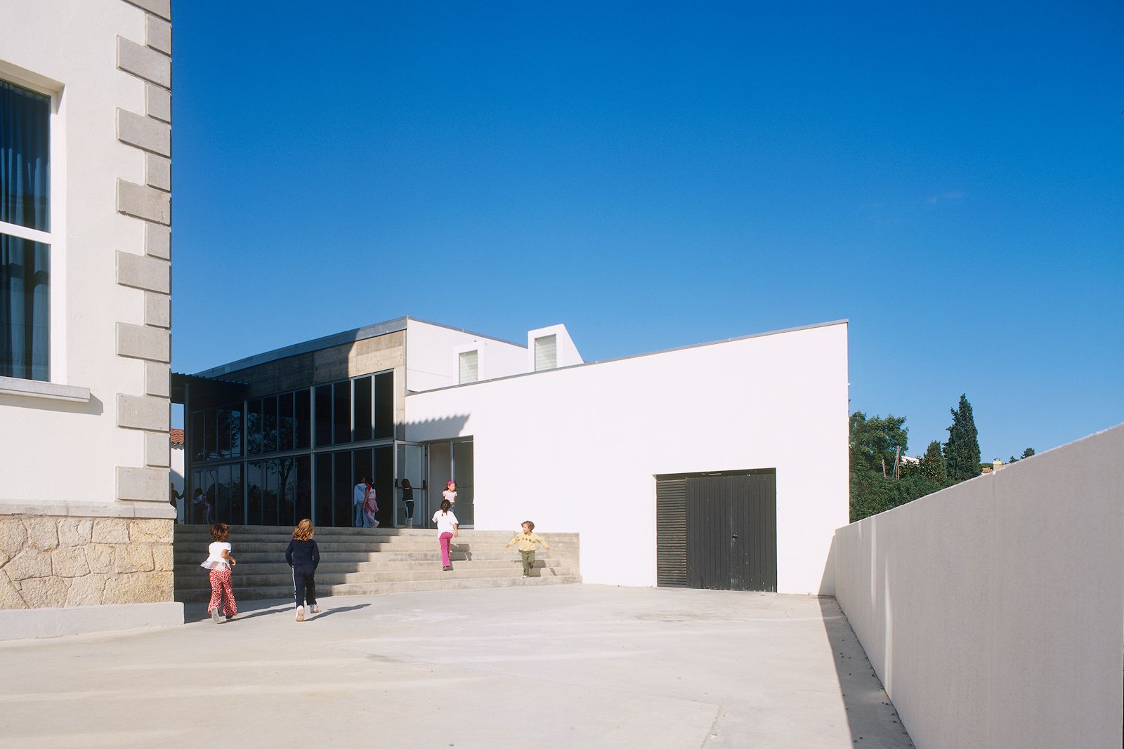Children playing in the courtyard of a modern school building.