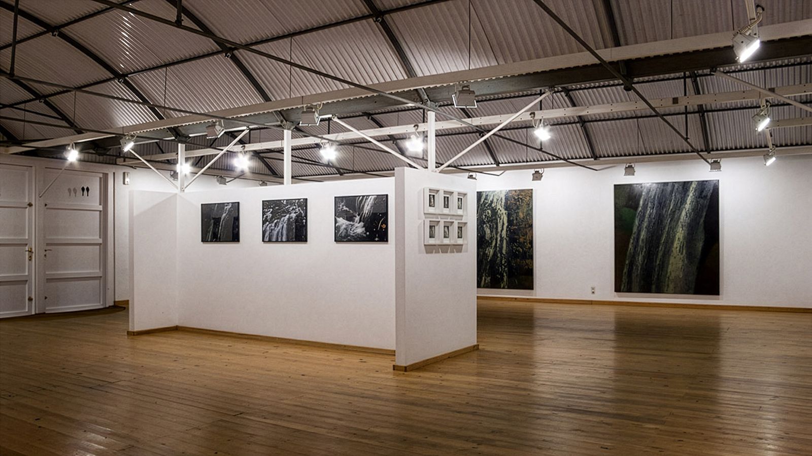 Galeria espaiosa amb obres d'art a les parets, terra de fusta i sostre de metall exposat.
