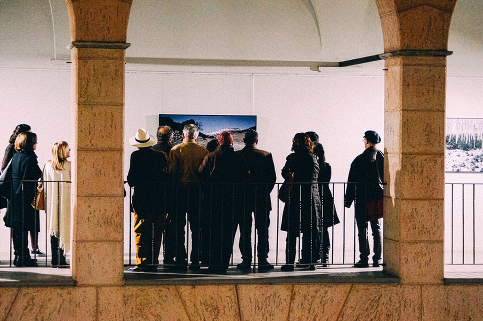 Un grupo de personas viendo fotografías en una sala de exposición.