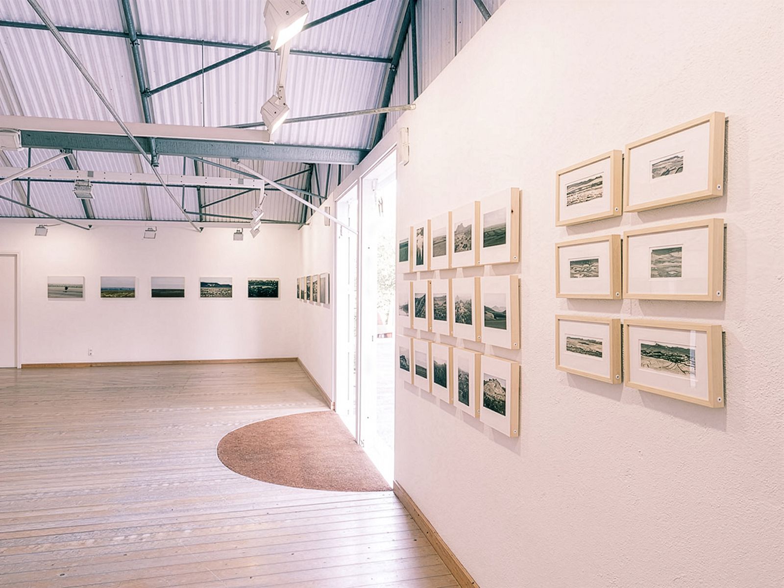 Espacio de exposición con obras de arte enmarcadas en las paredes.